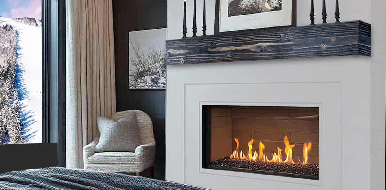 Modern bedroom with a fireplace, cozy chair, large window showing snowy trees, and neutral decor.